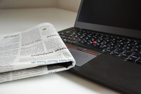 Hopvikt tidning med tysk text ligger på svart laptop