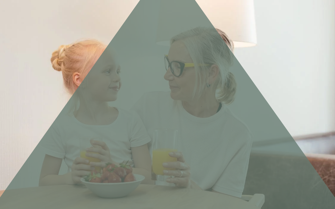 Ung flicka och äldre kvinna tittar på varandra vid frukostbord